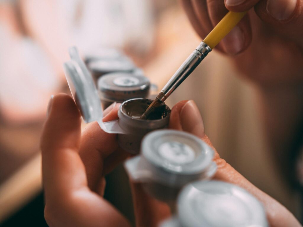 Close-up view of an artist mixing paint on a palette, showcasing the painting process and tools.